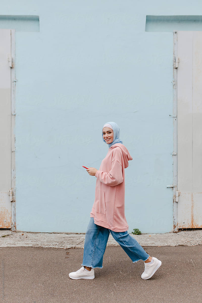 Stylish muslim woman in jeans, hoodie or longsleave, headscarf goes on the street and looks at the camera