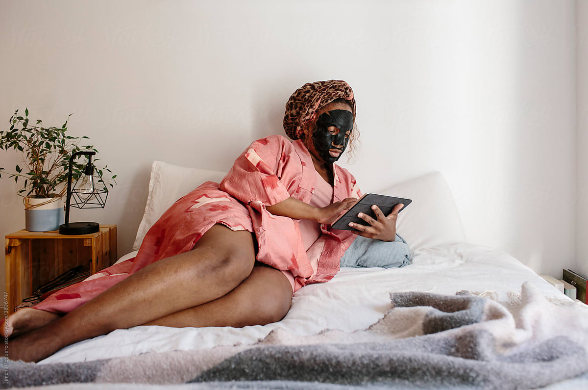 Woman with beauty mask on bed with device