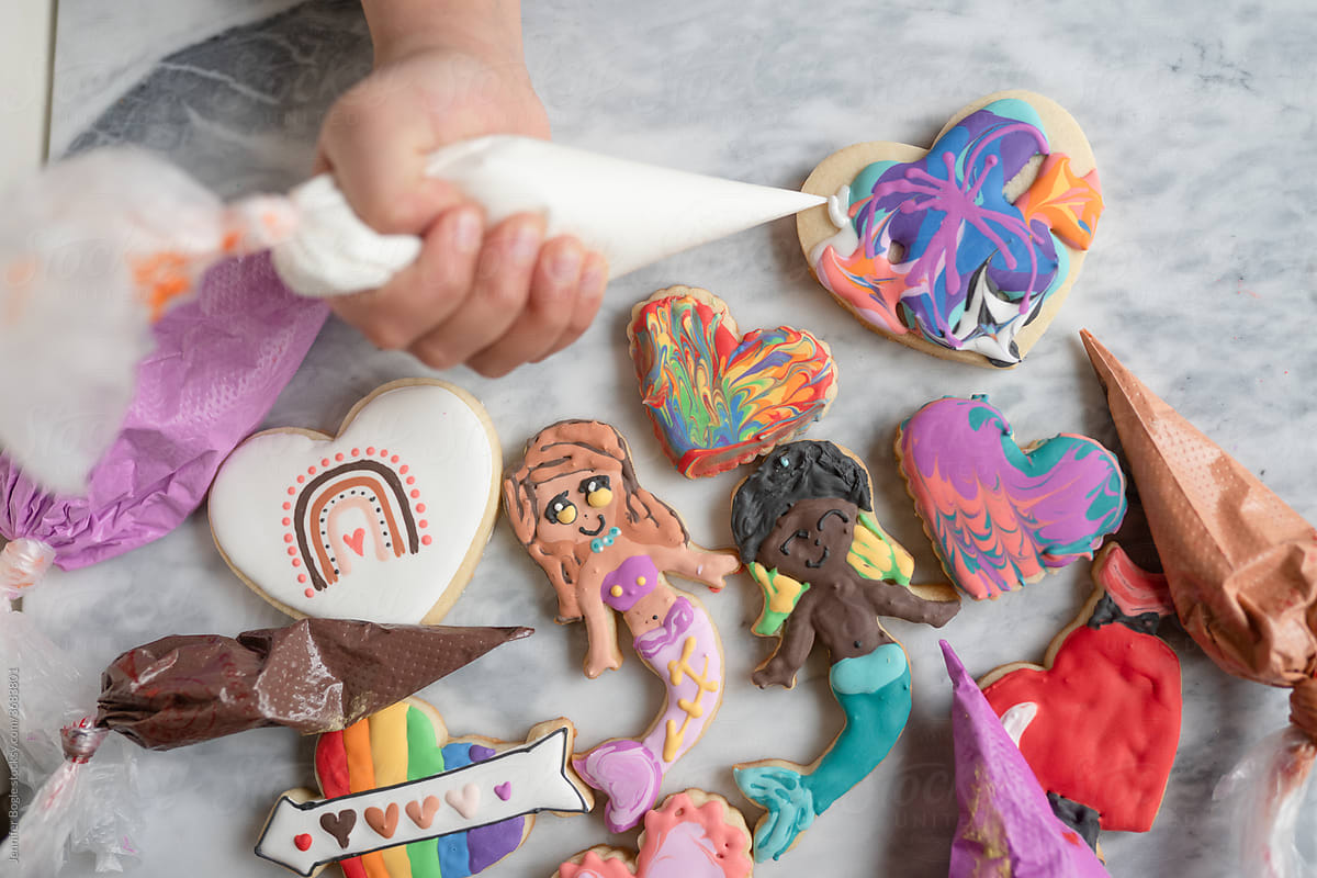 Child holding frosting bag with decorated cookies