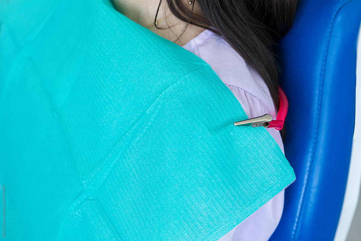 A dentist's patient wearing an aqua colored bib
