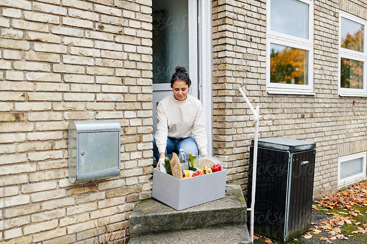 Woman picking up a grocery delivery at her door
