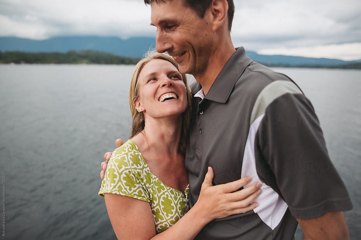 Happy couple in their 40\'s laughing on the dock at the lake