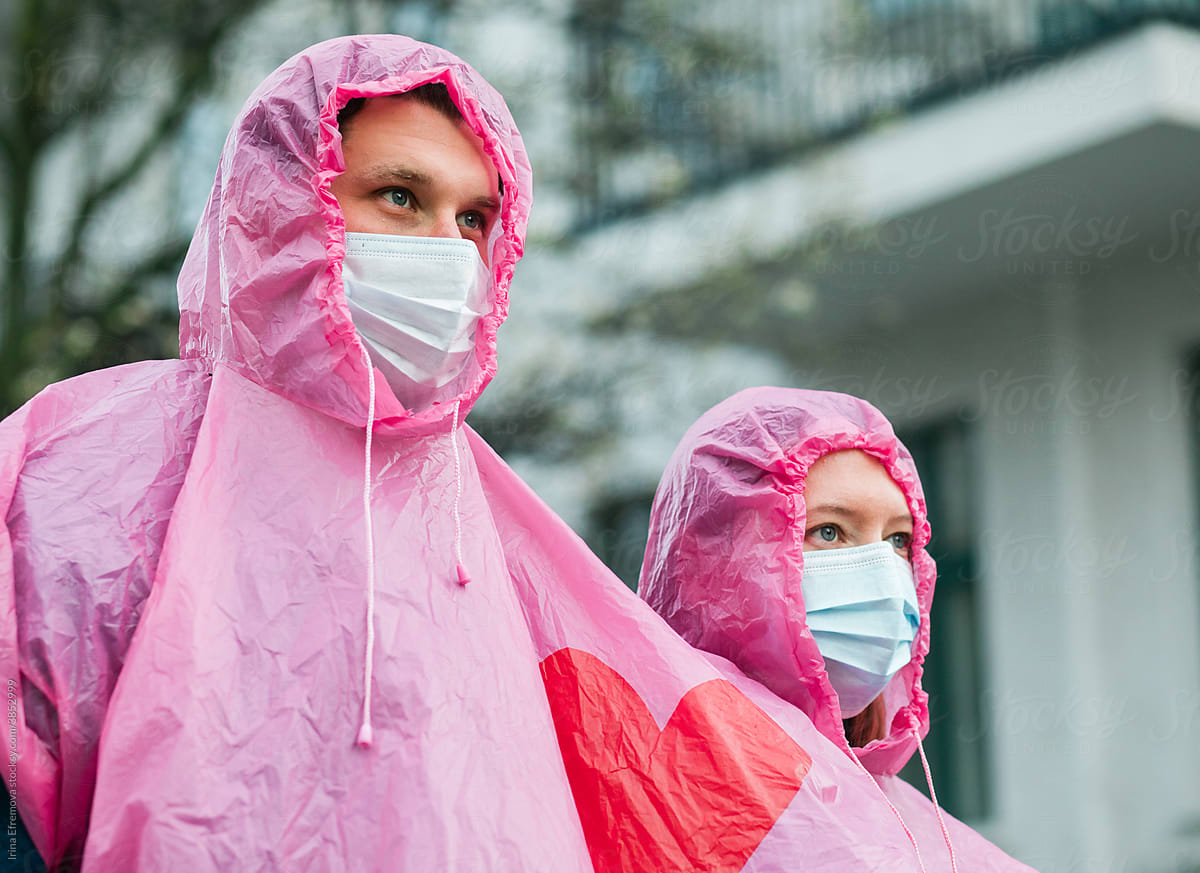 Man and woman wearing masks and pink raincoat