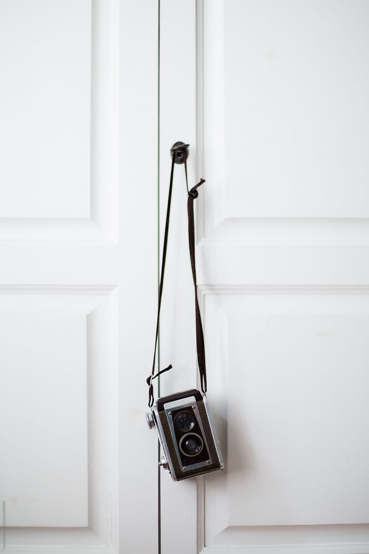 Old medium-format twin lens reflex camera hanging from white closet doors