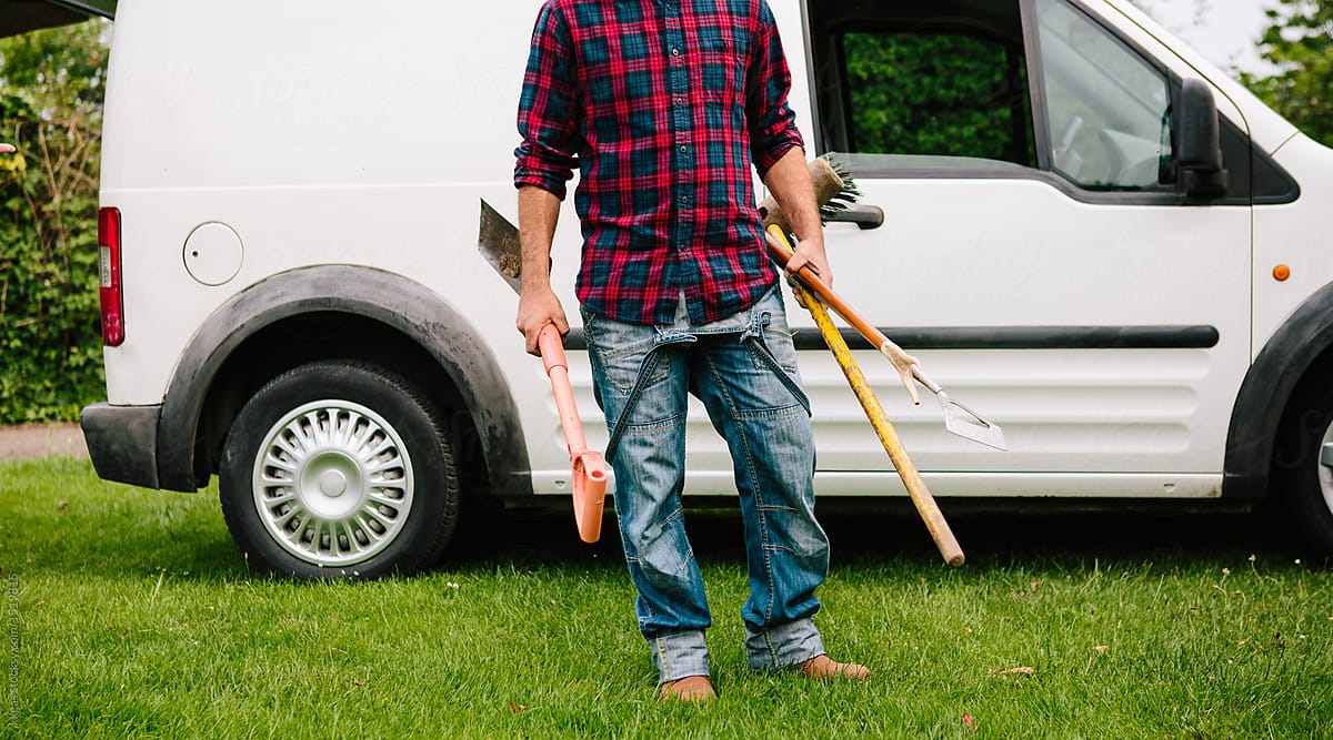 Anonymous male gardener with tools and van