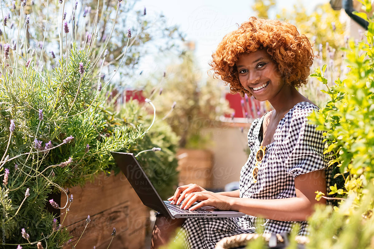 Cheerful black female using netbook on terrace