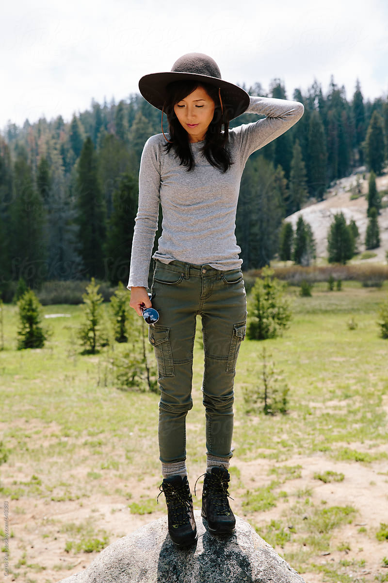 Asian woman standing on rock with mountain background
