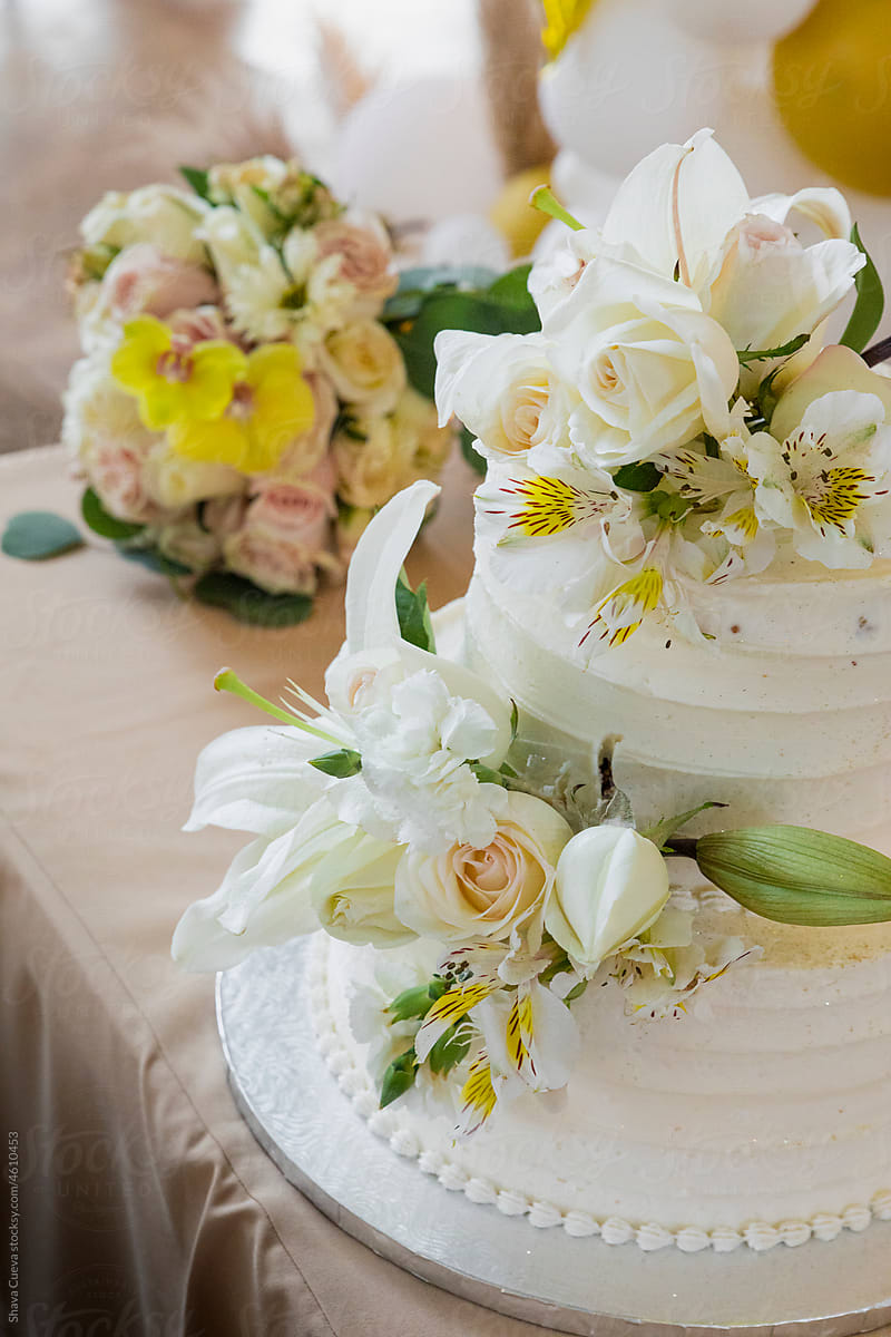 Wedding cake with roses on it next to a bouquet of flowers