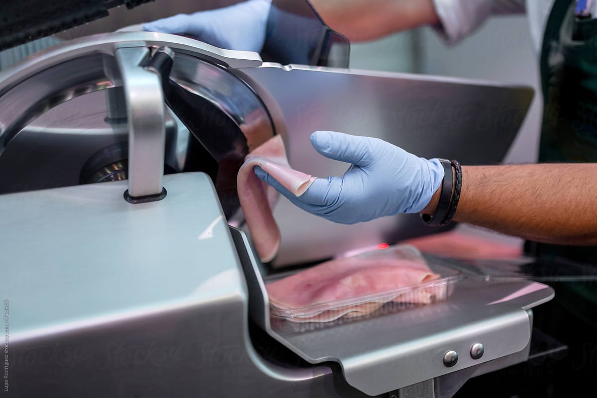 butcher cutting ham on a slicer