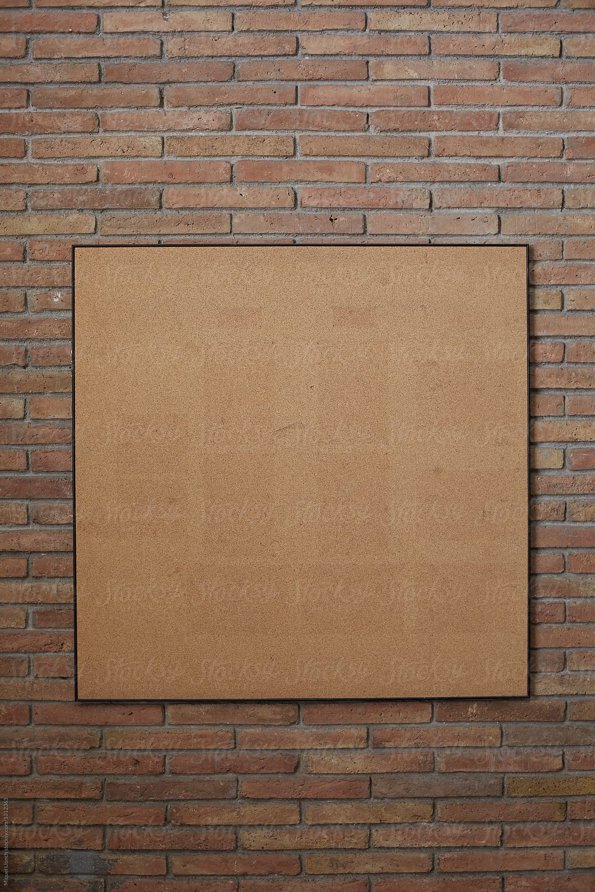 Empty corkboard on a brick wall