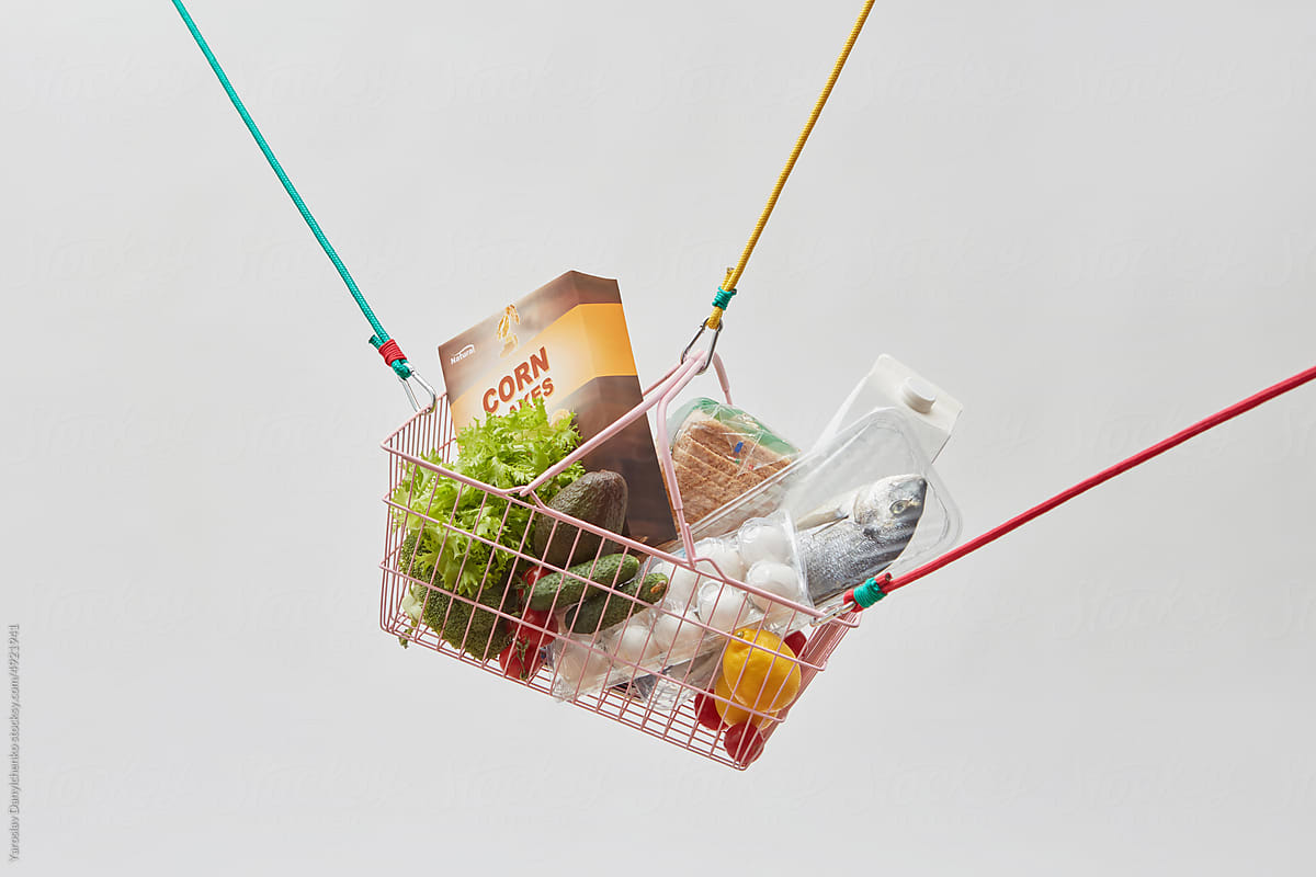 Fresh groceries in wire basket hung on ropes.