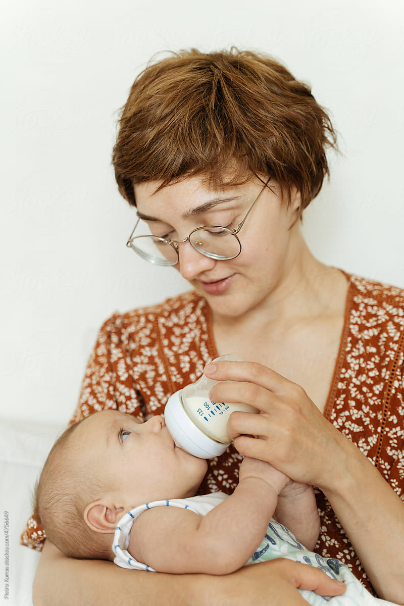 young mother feeding Newborn boy with formula from bottle