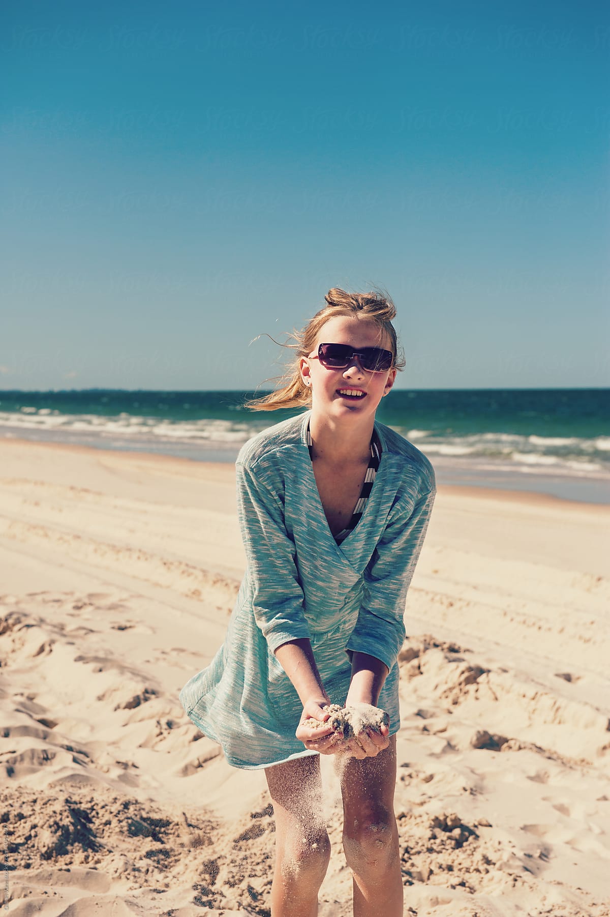 Tween Girl Playing In The Sand At The Beach, Wearing Sunglasses by