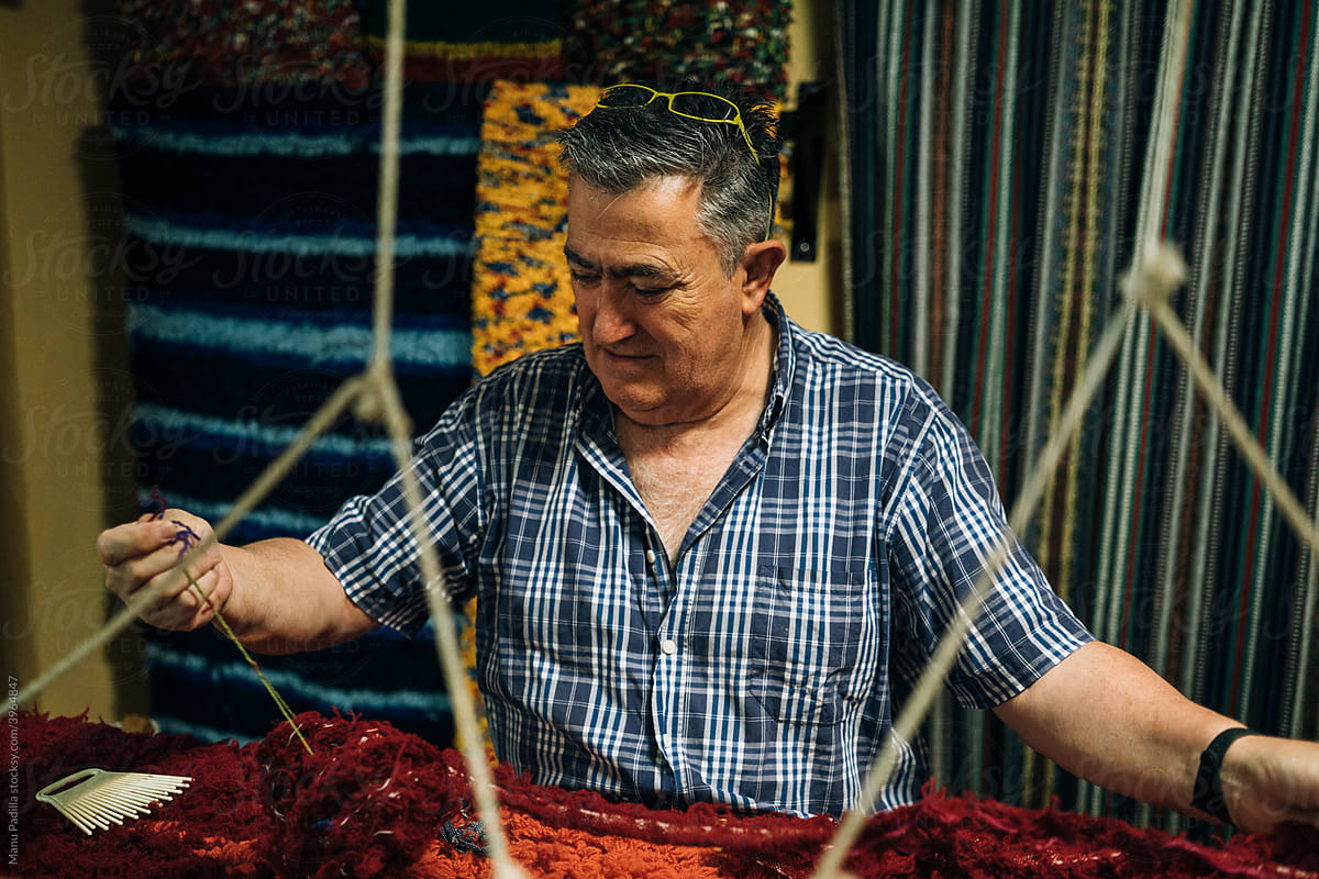 A Craftsman with a Blue Plaid Shirt Working a Loom