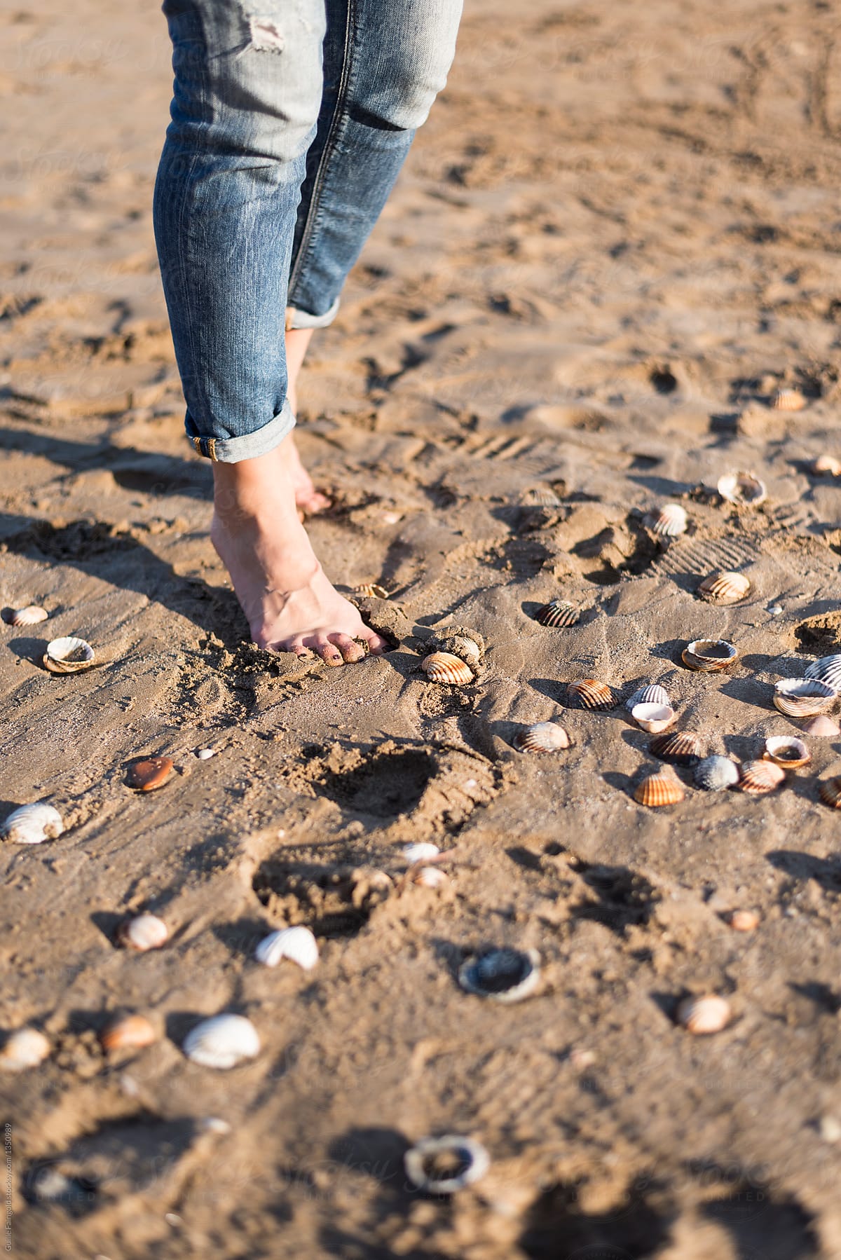 Woman walking on seashore with seashells.