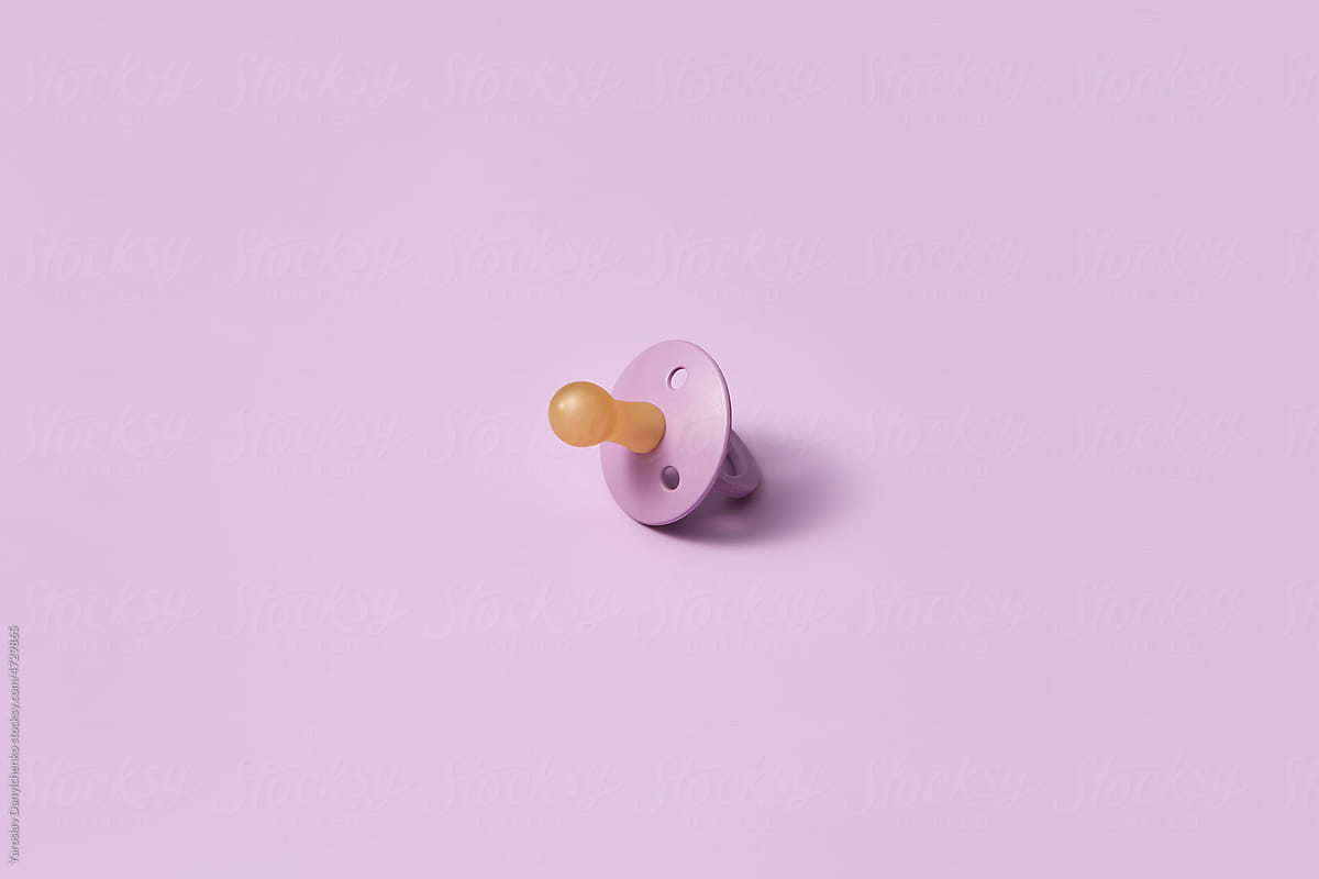 Single pacifier on pink background.