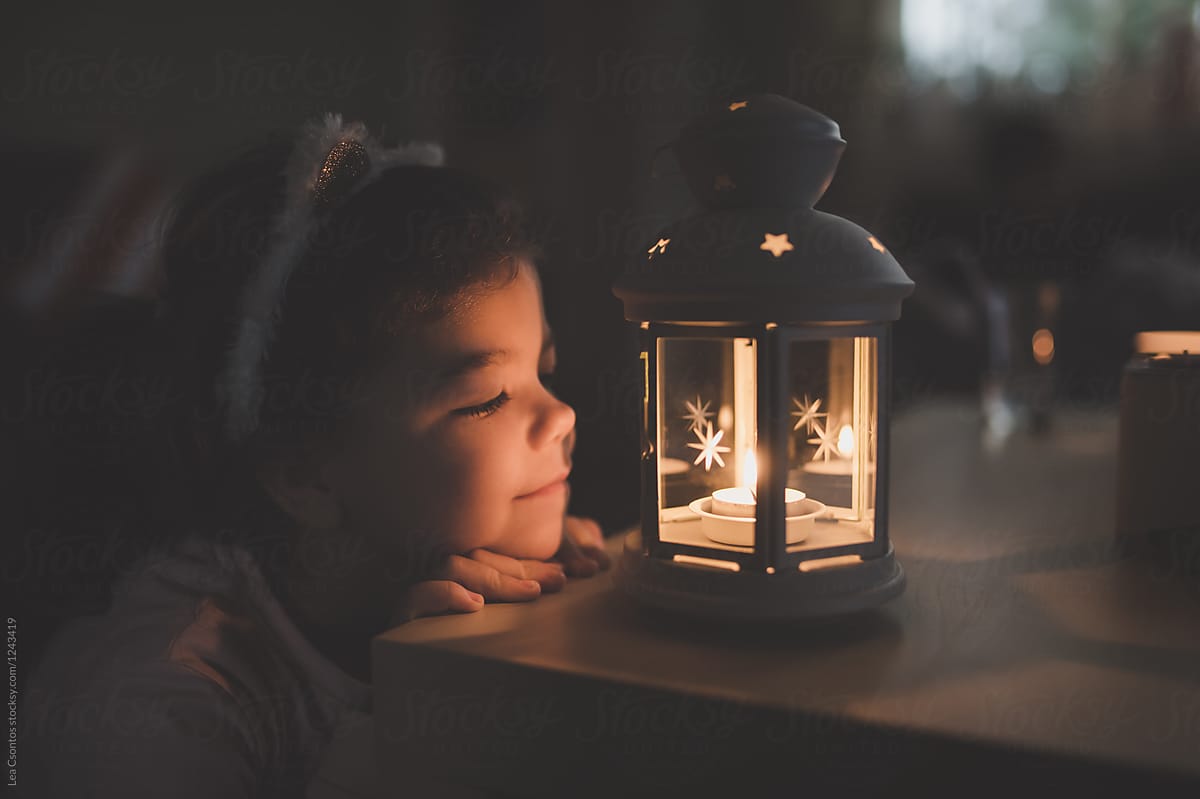 Child watching a candle in a lantern