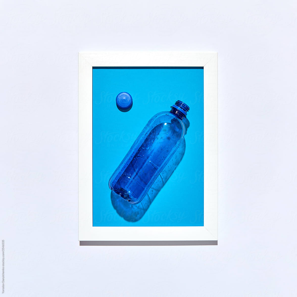 Plastic bottle with a cap in a frame on a light background.