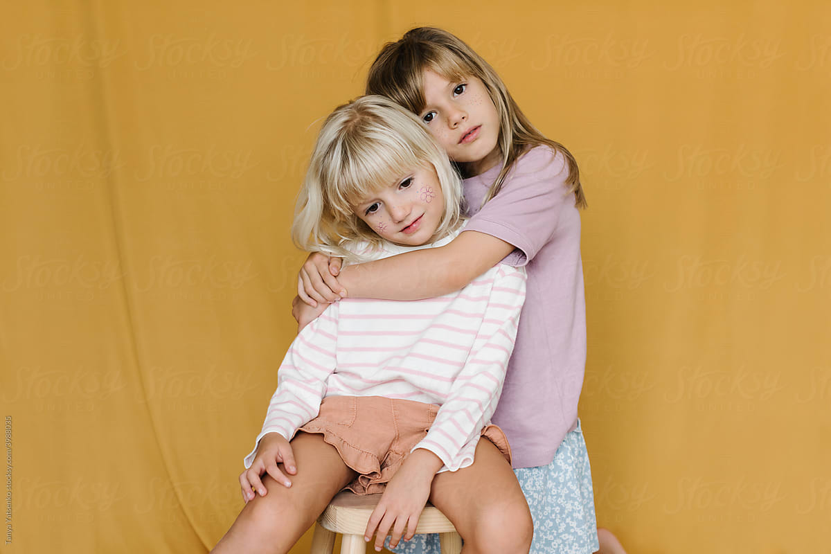 Portrait of two little girls over yellow backdrop