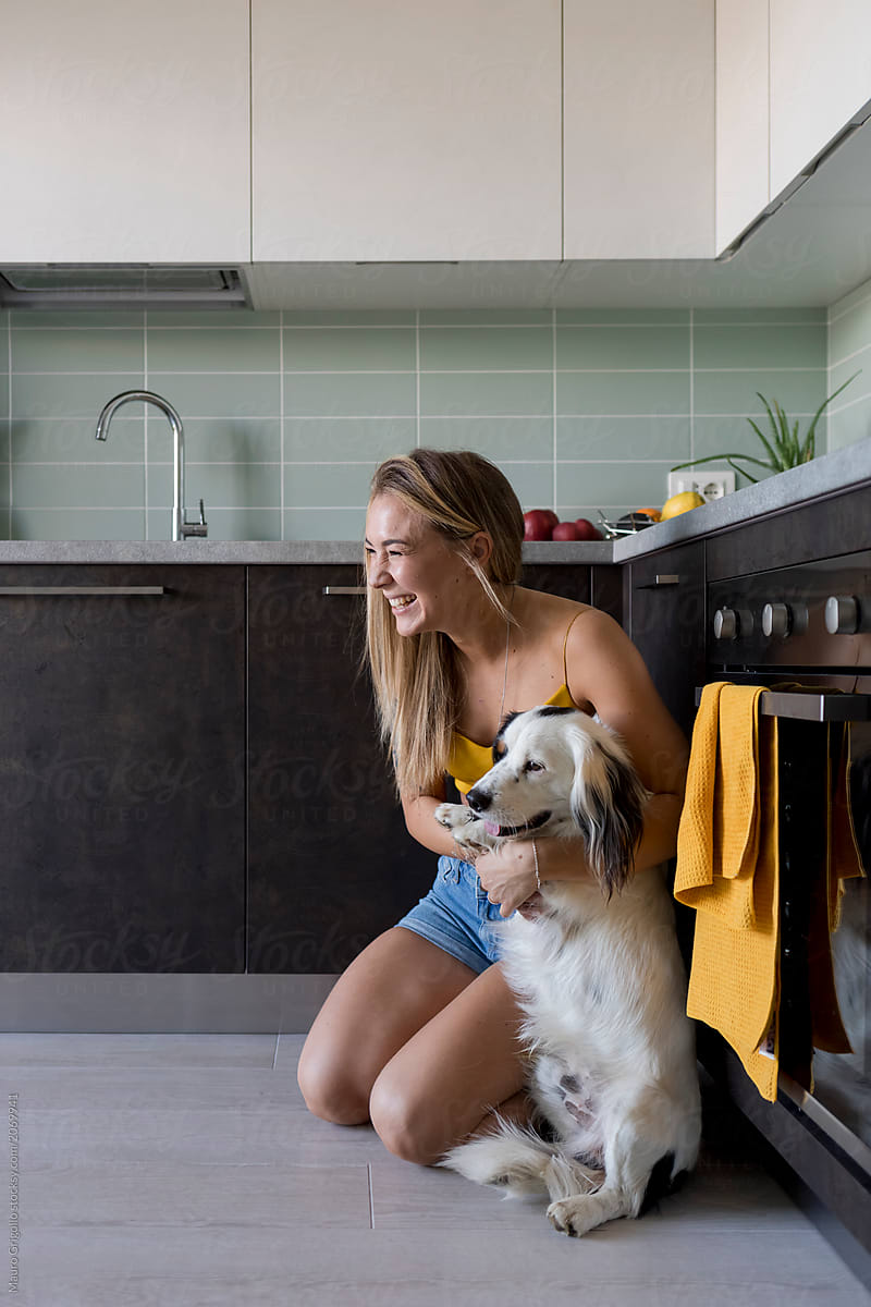 Happy woman playing with her dog indoors