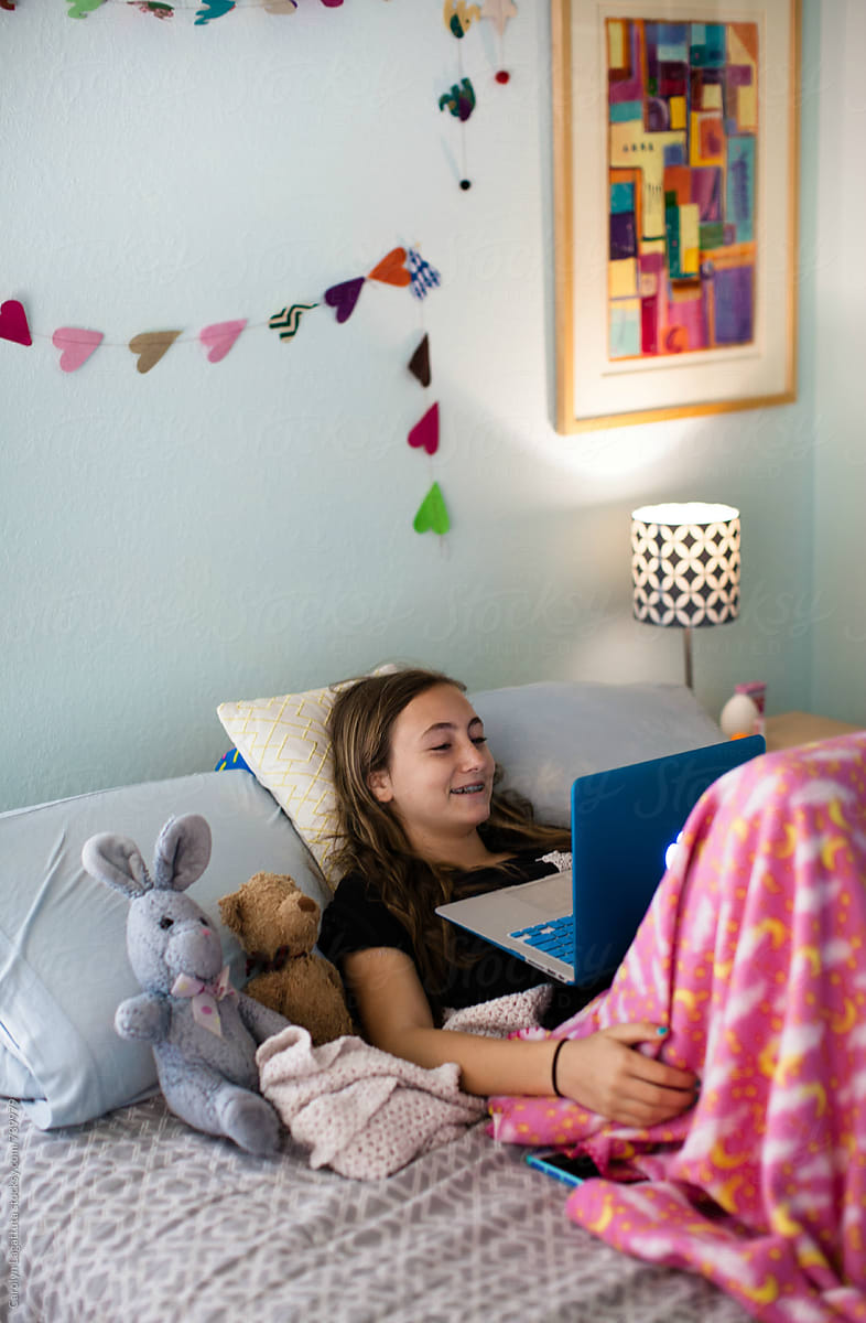 Teenage or tween girl sitting in her bedroom watching TV on her laptop