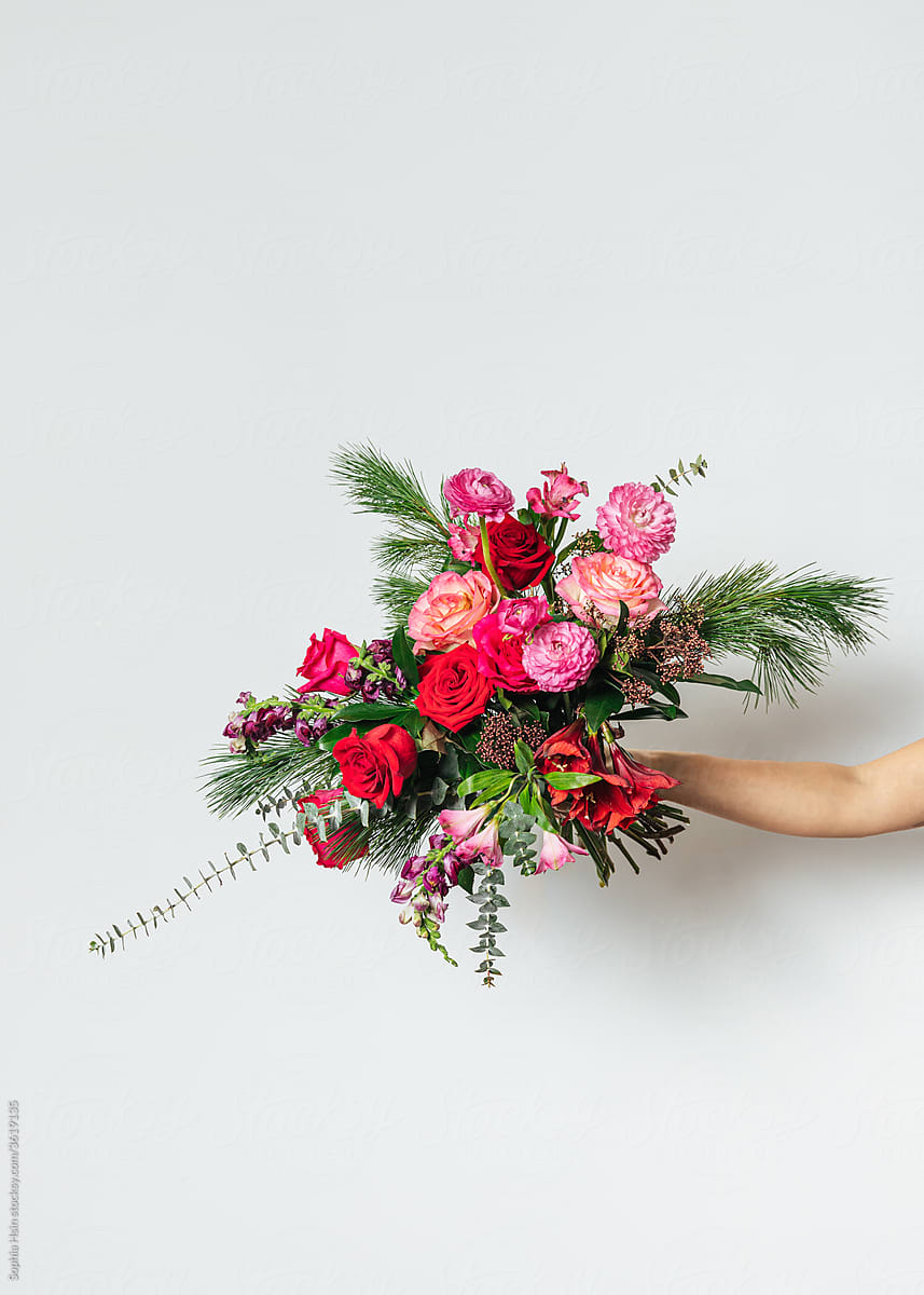 Hand holding bouquet of red and green flowers