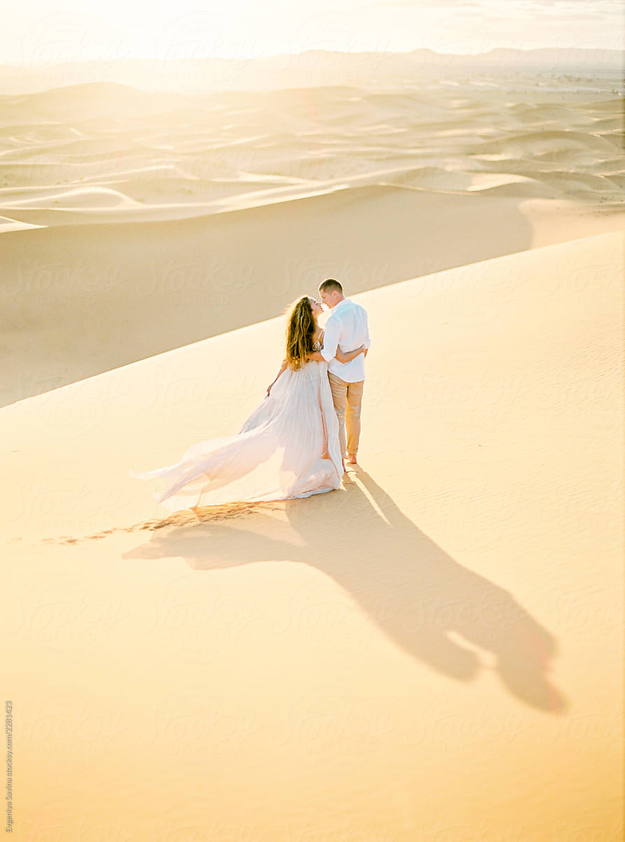 A Couple In The Desert Walking Into The Sunset By Stocksy Contributor
