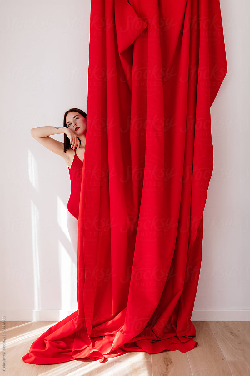 Beautiful young woman in bodysuit standing near curtain