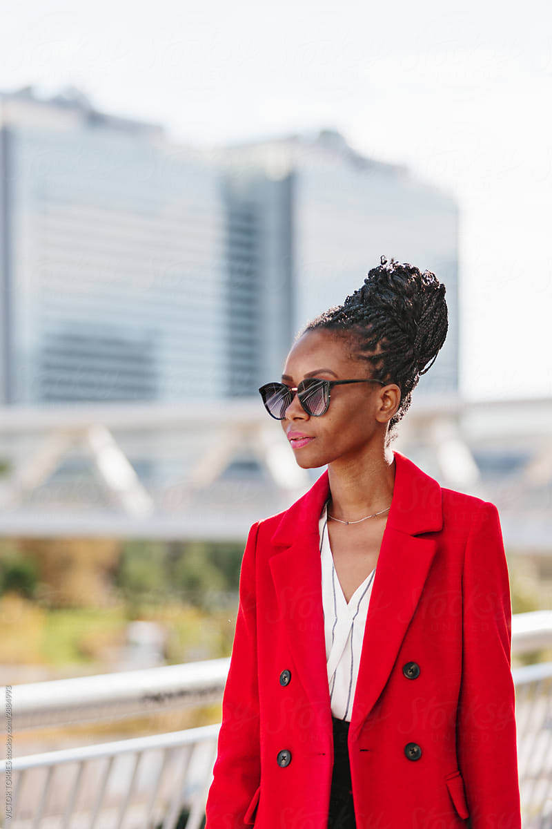Thoughtful black woman in sunglasses looking away in contrast light