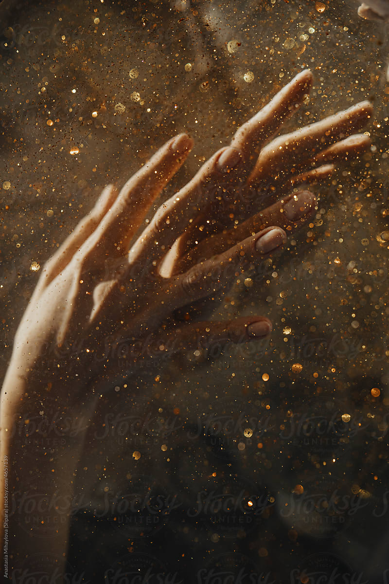 Photo of hands under water with gold glitter