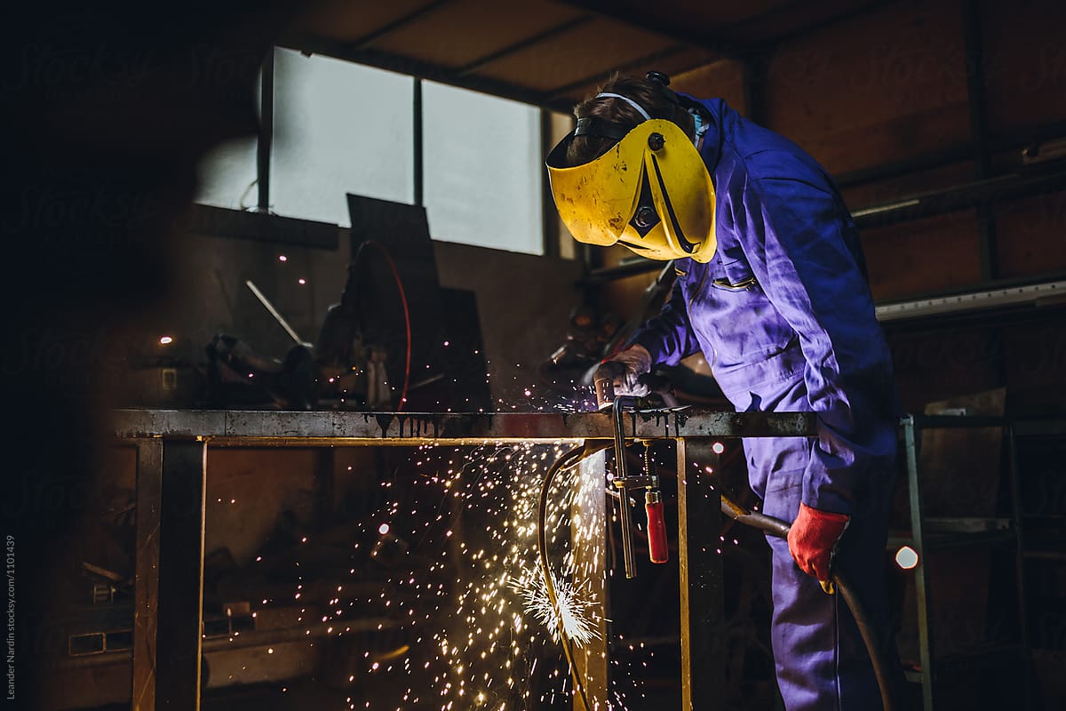 portrait of a metal worker with yellow protection mask operationg a plasma cutter