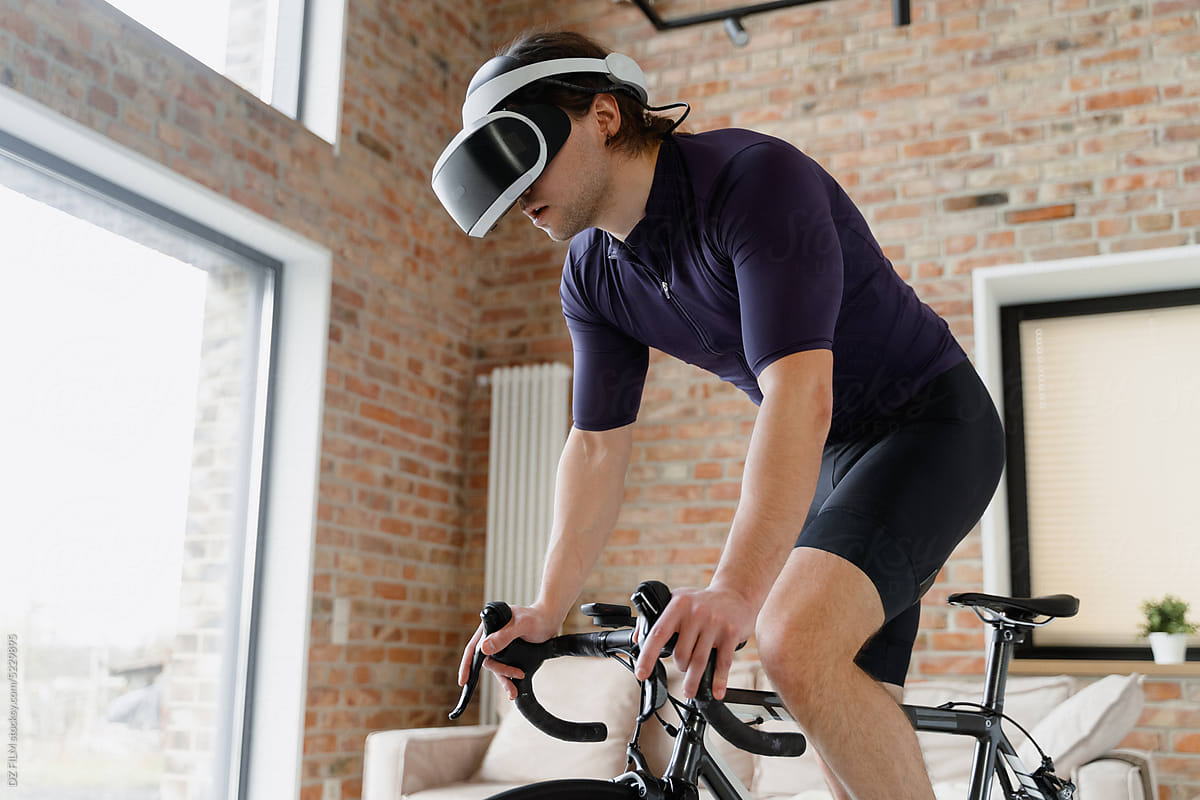 Man in virtual reality headset on exercise bike at home