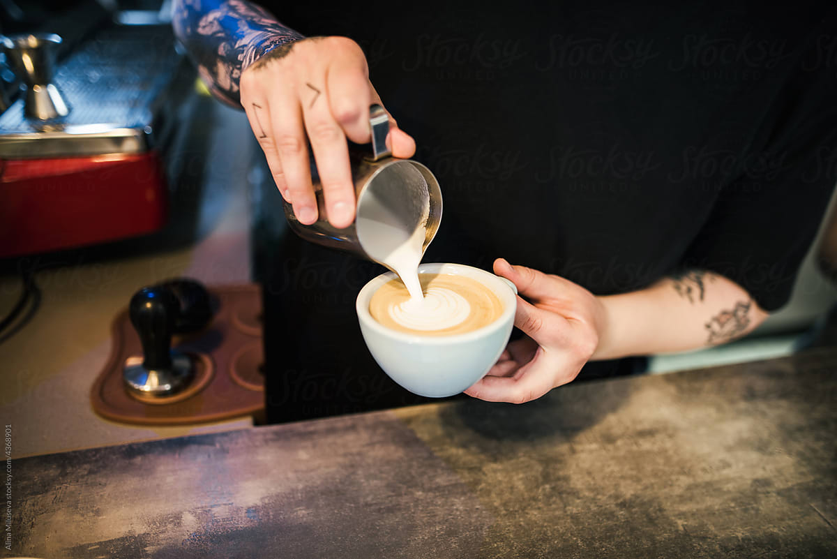 Crop shot of woman barista filling coffee with milk
