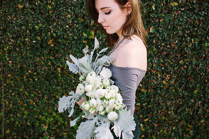 A woman holding a beautiful bouquet of white ranunculus.