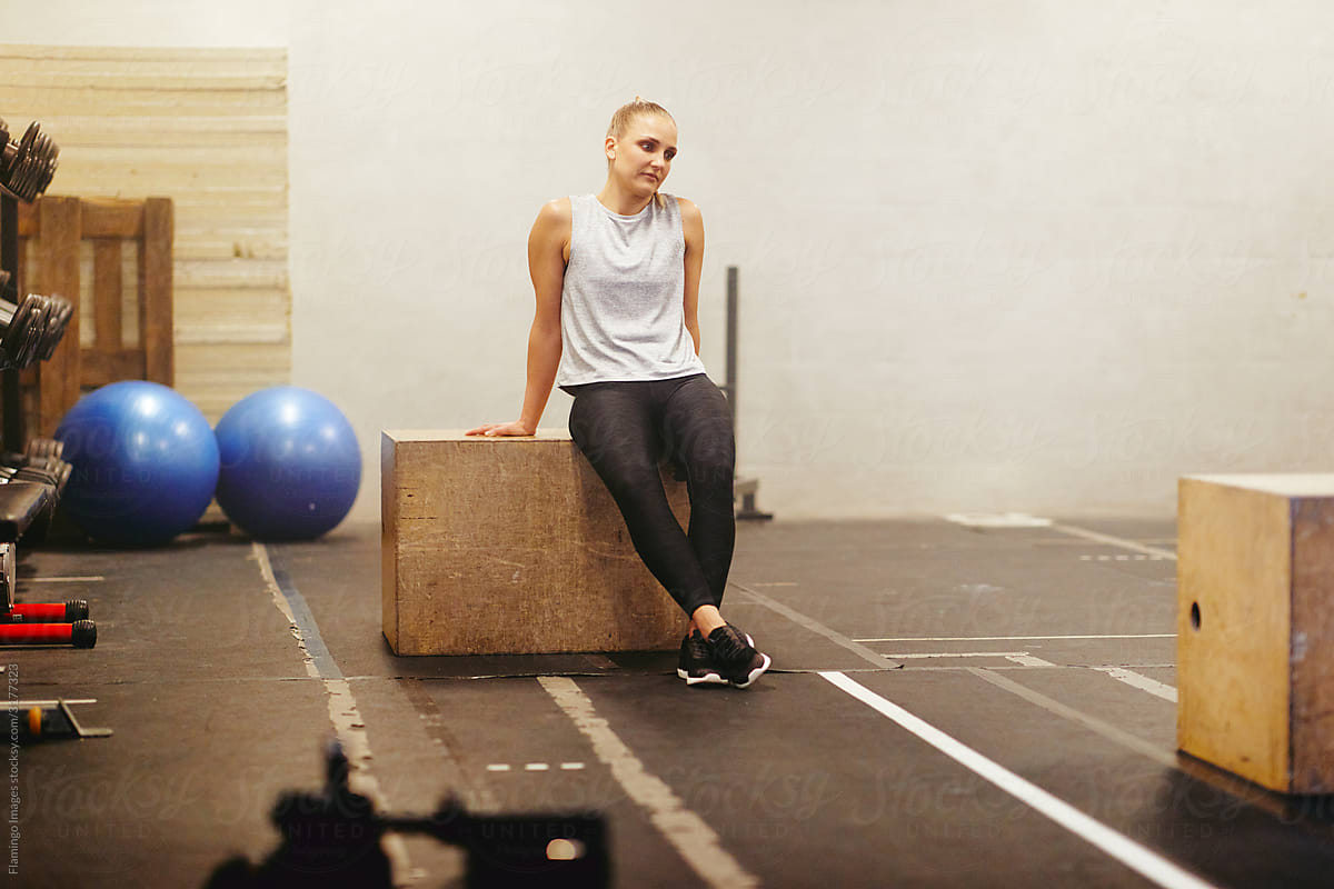 Fit young woman sitting on a box after a gym workout