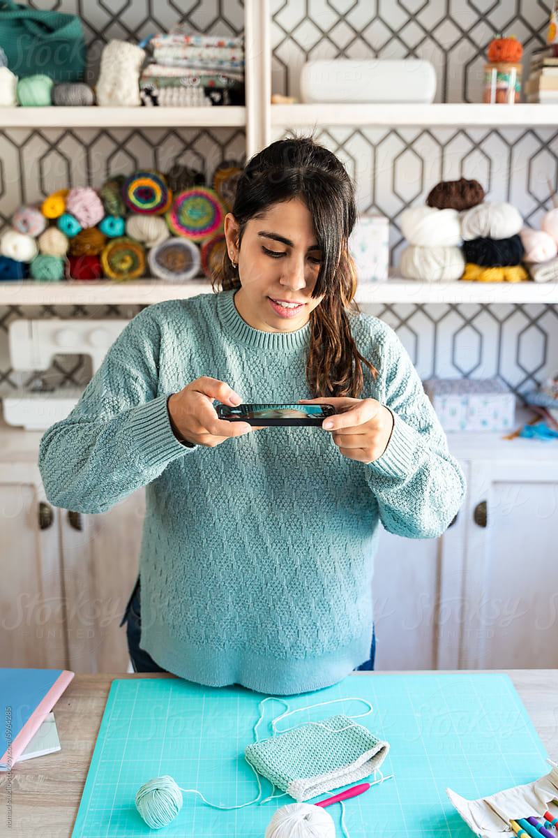 Woman knitting a small green piece in craft room