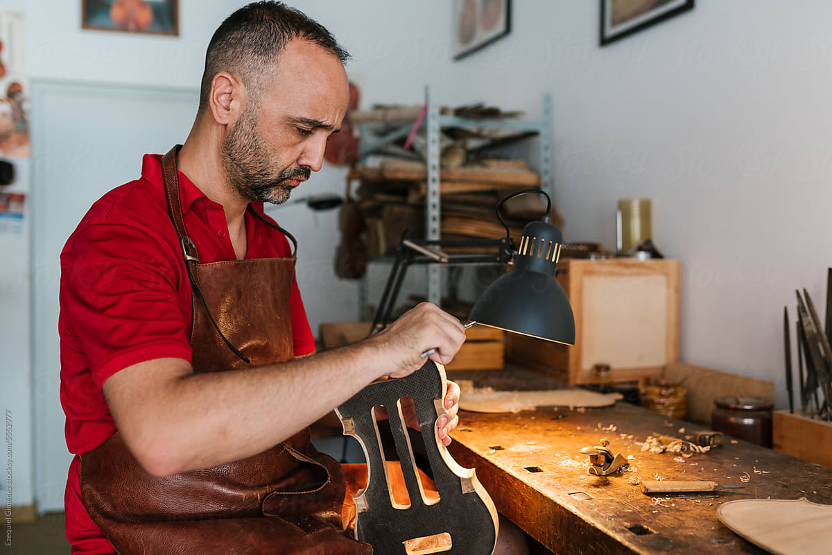 Professional luthier creating violin in workroom