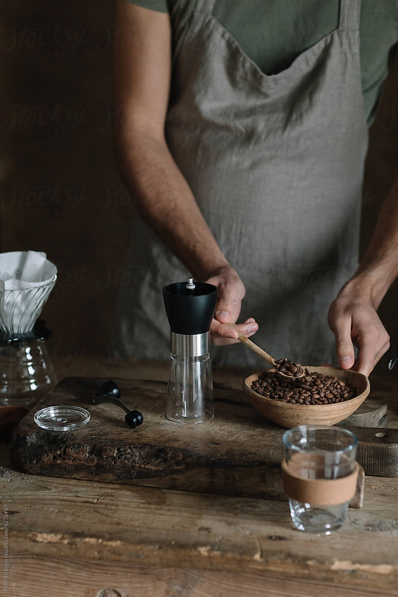 Man Putting Coffee Beans In Manual Grinder
