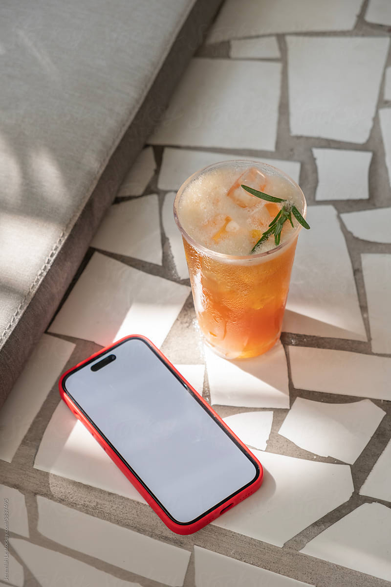 White Screen Of Mobile Phone and Glass of Summer Drink Under Sunlight