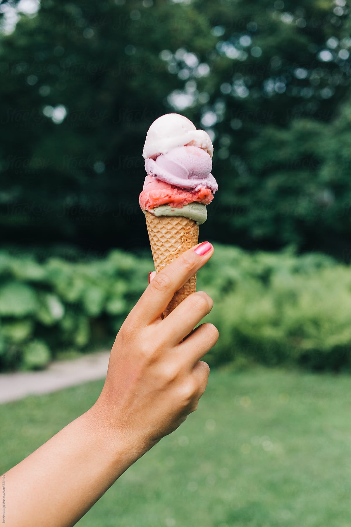 A woman\'s hand holding a colourful icecream in her hand