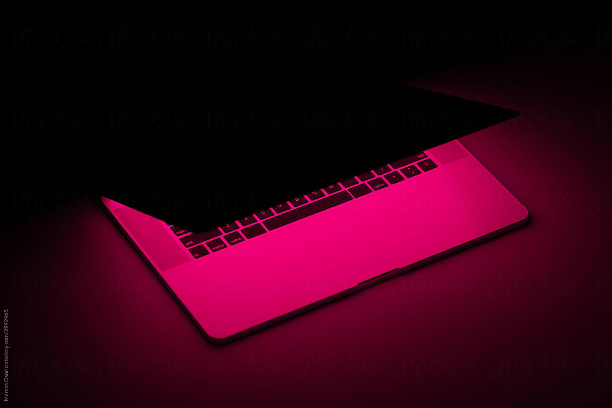 Laptop with fuchsia neon light illuminated screen ready to play