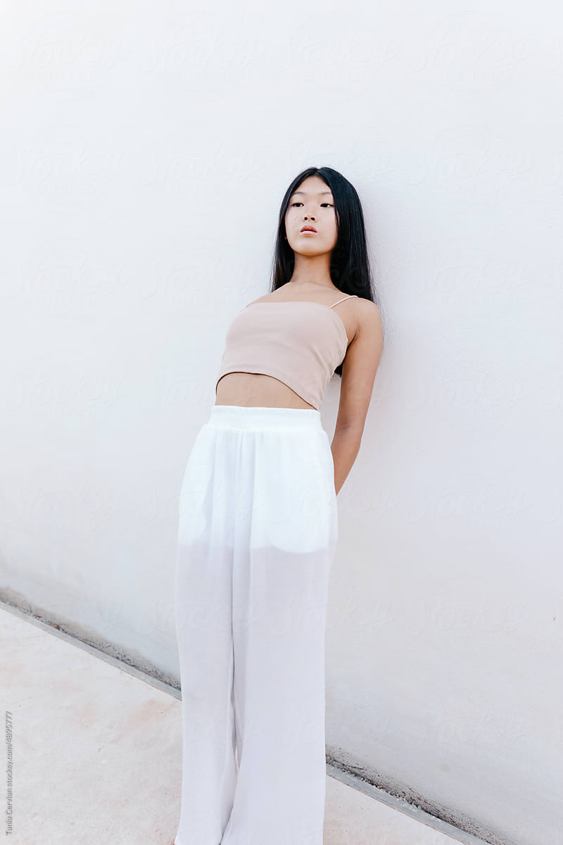 Young Asian woman leaning on wall