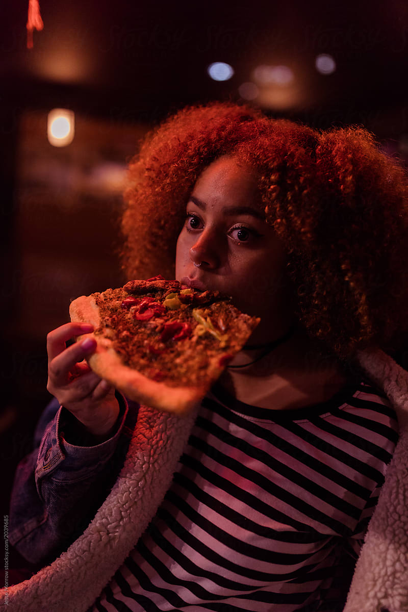 teenager eating slice of pizza