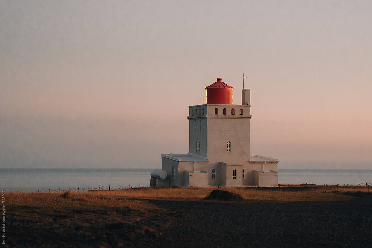 picturesque lighthouse is illuminated by the pink light of a sunset