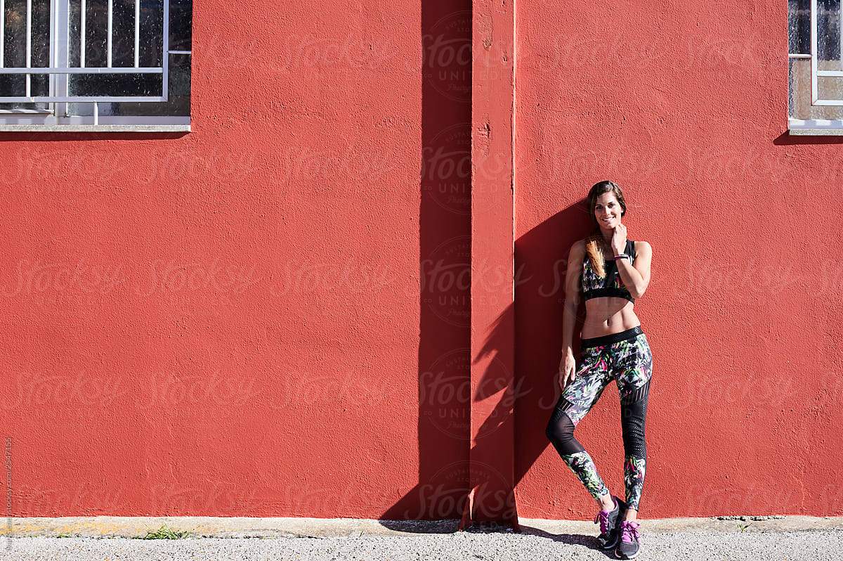 Smiling fitness blonde woman red wall.