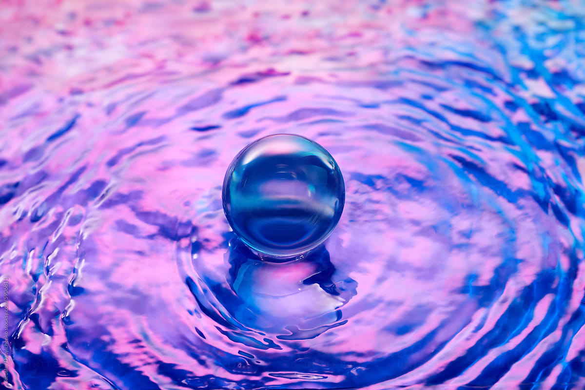 Blue and pink colored water surrounding transparent ball