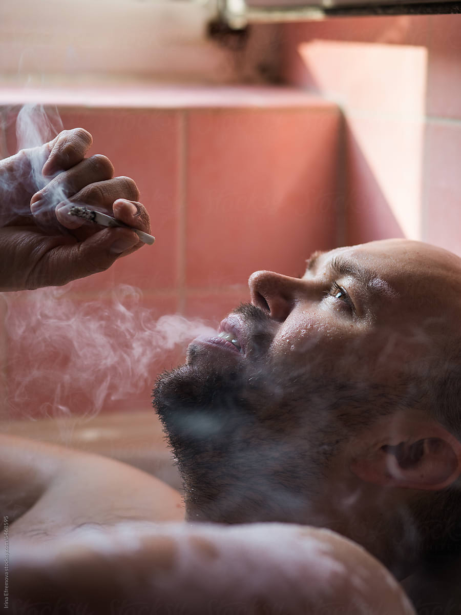 Man Smoking a Joint in a Pink-Tiled Bathroom