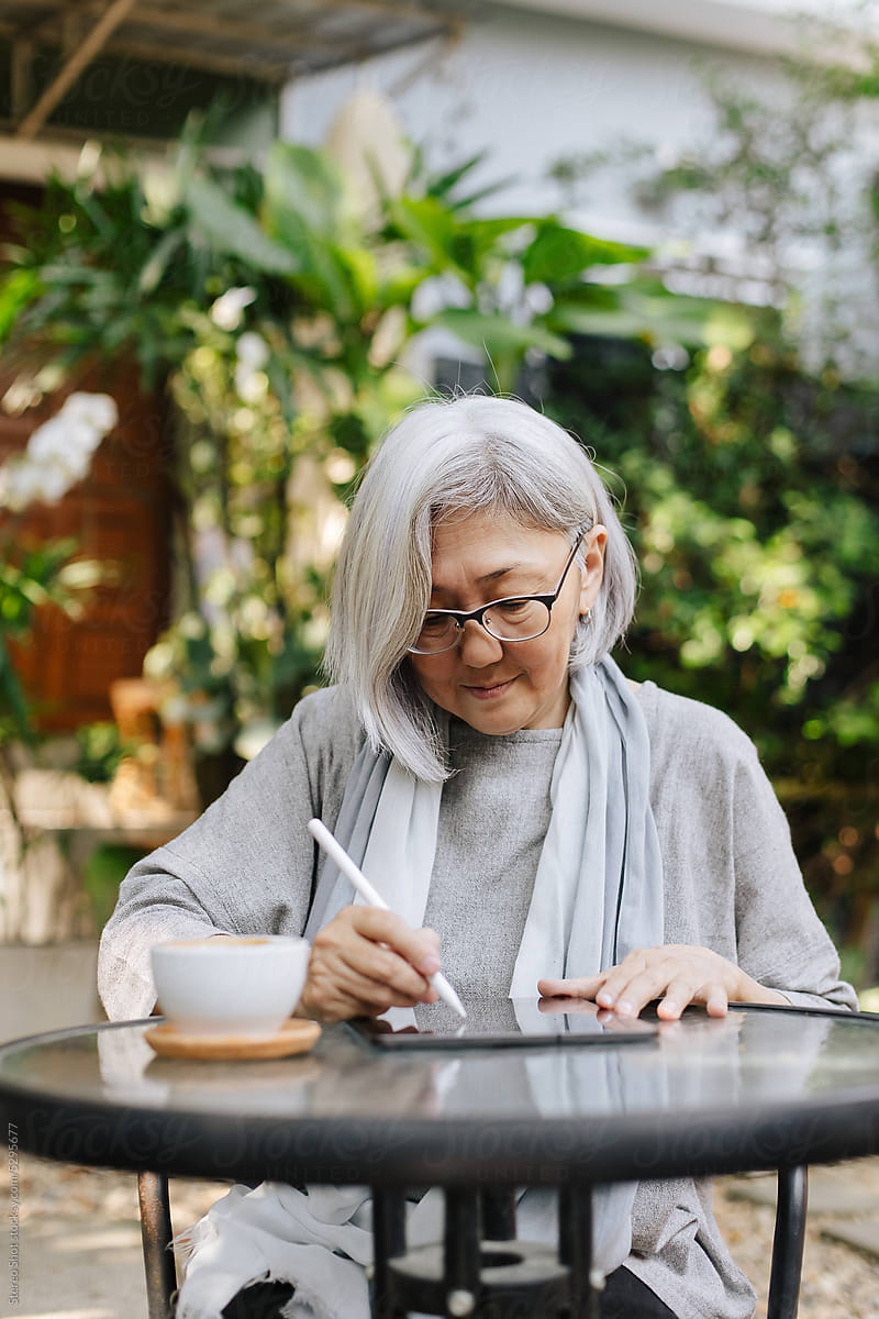 Senior woman drawing with stylus on tablet