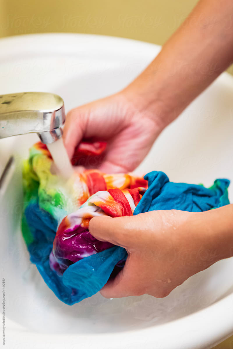 Teen unwrapping and rinsing dye from a tie dyed t-shirt
