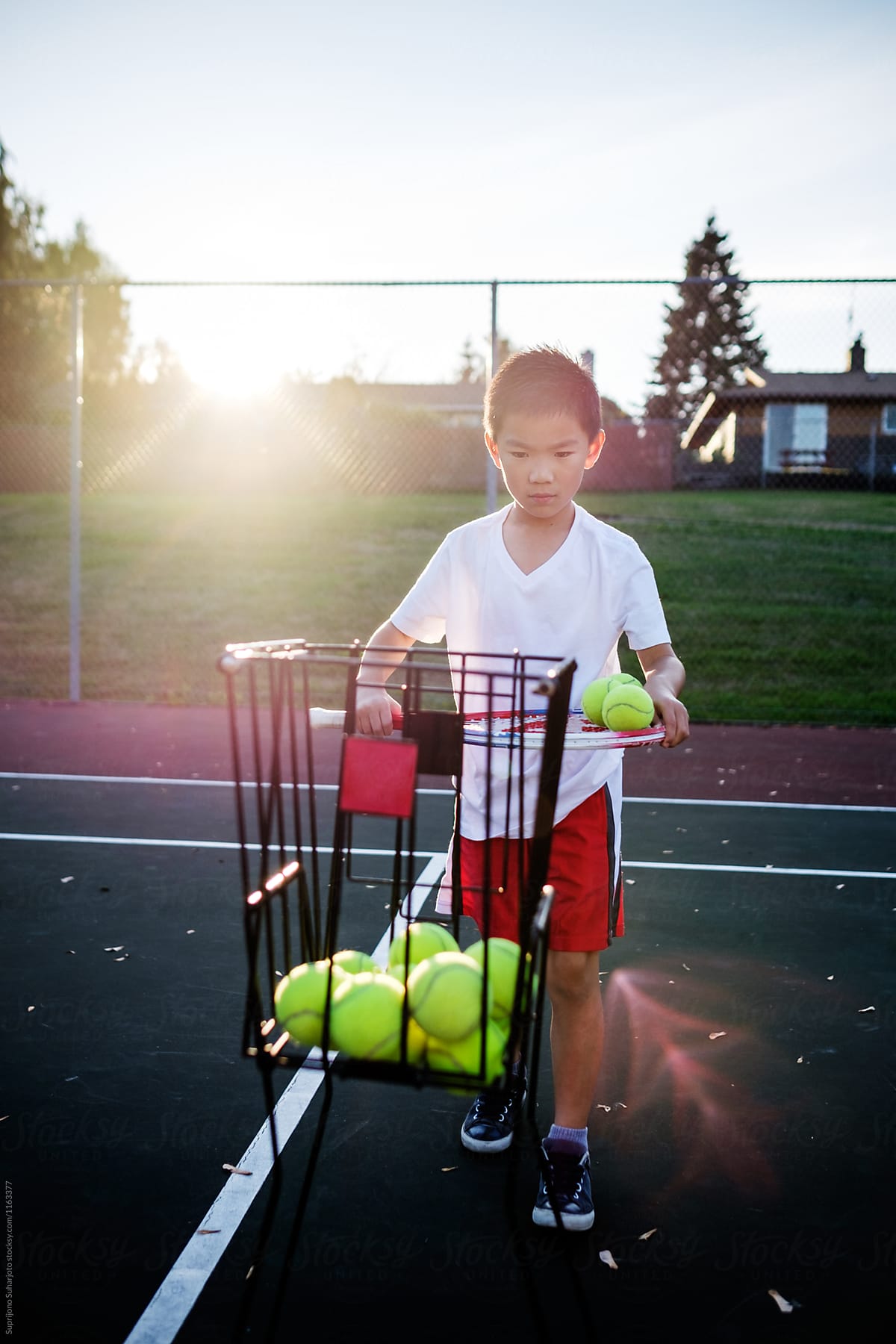 Asian kid playing tennis on the outdoor tennis court